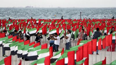 People take photos next to hundreds of UAE flags on the National Day weekend. Pawan Singh / The National
