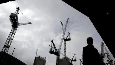 A pedestrian walks past construction cranes as they work above a building site in London. UK GDP rose 0.9 per cent in the first quarter, up from 0.7 per cent in the final three months of 2013, according to the median of estimate in a Bloomberg News survey of economists. Simon Dawson / Bloomberg