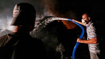 Volunteers use a hose to douse the flames as a wildfire takes hold in Mugla, Turkey. AFP
