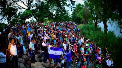 Migrants cheer at the rest who are still waiting to cross at the border. AFP