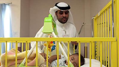 Basil Hussein, a volunteer at Al Qassimi hospital, tends to Omar.