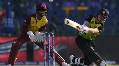 Australia's David Warner (R) plays a shot as West Indies' wicketkeeper Nicholas Pooran watches during the ICC men’s Twenty20 World Cup cricket match between Australia and West Indies at the Sheikh Zayed Cricket Stadium in Abu Dhabi on November 6, 2021. (Photo by INDRANIL MUKHERJEE / AFP)