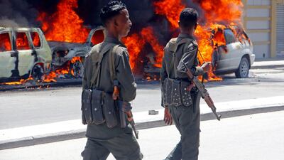 Soldiers walk past cars burning after car bomb detonated in Mogadishu, Somalia. AP
