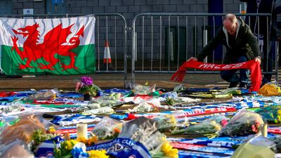 A man adds a Wales scarf to the display of Cardiff City tributes to the football club's new signing Emiliano Sala, whose flight disappeared from radar over the English Channel. AFP.