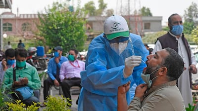 A health official wearing protective gear takes the sample of a man at a drive-through screening and testing facility in Islamabad. AFP
