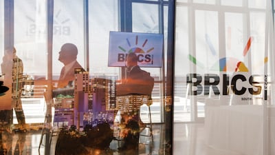 Delegates walk past logos of the Brics summit at the Sandton Convention Centre in Johannesburg on August 23. Pool/ AFP