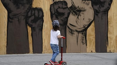 A child rides a scooter past a mural by artists Malik Crawford and Jerome Tiunayan on a boarded-up store in the Union Square section of New York. US. AFP