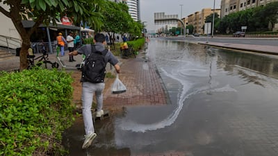 Pedestrians navigate the water on Jebel Ali Racecourse road in Dubai. Antonie Robertson / The National