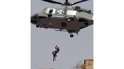 A member of the UAE Air Force descends from a helicopter to rescue a young man from a rooftop in Abu Dhabi's Airport Road during a fire.