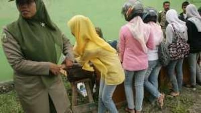A Sharia policewoman escorts women dressed in tight jeans during a street inspection in Banda Aceh.