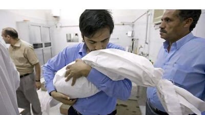 Hassan Bakari carries the wrapped body of his son, Suhail, in Ajman last March. The boy died from toxic fumes of pesticides.
