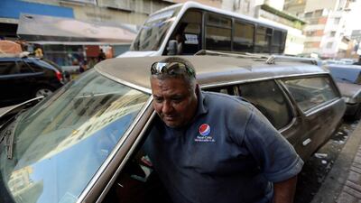 Ruben Ruiz emerges from his 1975 Ford LTD station wagon in Caracas, where the steady roar of Nixon-era gas guzzlers is sounding a little less muscular. Fernando Llano / AP