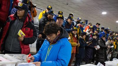 A trader writes on a piece of paper as others look on during an auction for oysters held by the Oyster Hanging Culture Fisheries Cooperatives in Tongyeong.