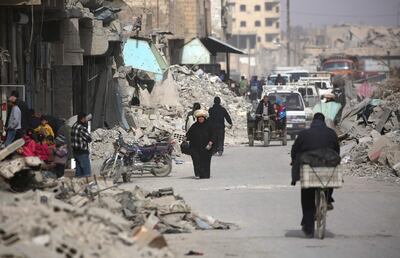 Syrians walk amid debris of destroyed buildings in the northern Syrian city of Raqqa on January 11, 2018 after a huge military operation by Kurdish fighters on the ground and US warplanes defeated ISIL but also left the city completely disfigured. Delil Souleiman / AFP