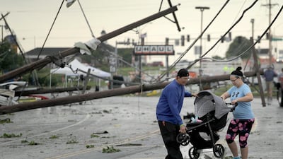 Jessica Rodgers and neighbour Ray Arellana carry a stroller carrying Rodgers' sister Sophia Rodgers over downed power lines after a tornado tore though Jefferson City, Missouri. AP Photo