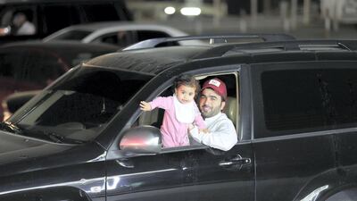 An Emirati man takes his daughter rounding as he waits for a cup of tea from a cafeteria in Ras Al Khaimah. Chris Whiteoak / The National