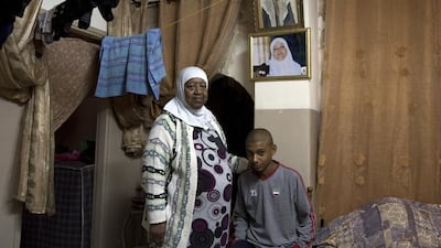 Afro Muslim woman Zohar Kardi with her 14-year-old grandson, Smayeen, as they stand by portraits of Zohar’s parents.
