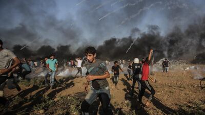 Palestinian protesters run for cover from Israeli tear-gas during the clashes with Israeli troops near the border with Israel in eastern Gaza Strip, on Friday July 27. EPA