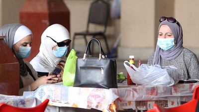 Kuwaiti women wear protective masks as they sit in a restaurant inside the Mubarakiya Market in Kuwait City. AFP
