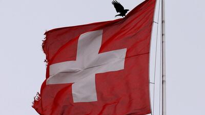 A bird lands on a Swiss national flag in Zurich, Switzerland. Reuters