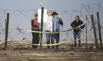 A woman gestures toward Mexico from behind concertina wire on the beach on the U.S. side of the US-Mexico border on January 10, 2019. Getty