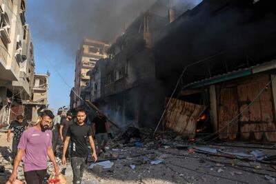 Palestinians walk amid the rubble of a building hit in an Israeli air strike on October 13. AFP