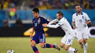 Shinji Kagawa, left, of Japan controls the ball against Dimitris Salpingidis of Greece during their 2014 Fifa World Cup Group C match at Estadio das Dunas on June 19, 2014, in Natal, Brazil. Jamie McDonald / Getty Images