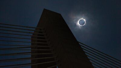 A solar eclipse shows through a layer of clouds over the Ravenel Bridge in Charleston, South Carolina. Wade Spees / The Post And Courier via AP
