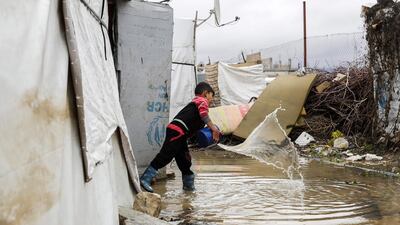 A Syrian child uses a bucket to bale out water from his tent at a refugee camp on the outskirts of the town of Zahle in Lebanon's Bekaa Valley. Joseph Eid / AFP