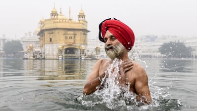 A Sikh devotee takes a dip in the holy sarovar (water tank) on the occasion of Bandi Chhor Divas, a Sikh festival coinciding with Diwali, the Hindu festival of light, at the Golden Temple in Amritsar on November 14, 2020. / AFP / NARINDER NANU