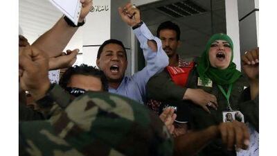 Ibtisam Saadeddin, 35, right, a khaki-clad female soldier wearing a green Muslim headscarf and Libyan leader Muammar Qaddafi's pin on it, shouts pro-Qaddafi chants at the women-only Gurji fuel station in Tripoli, Libya.