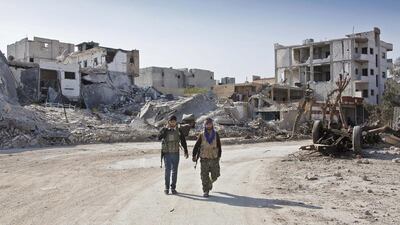 File photo of Kurdish People's Protection Units (YPG) soldiers walk near the town entrance circle heading to their strongholds in Kobani, Syria. Amnesty International said the US-backed Kurdish administration in northern Syria has displaced thousands of mainly Arab citizens and demolished their homes. Jake Simkin,/AP Photo
