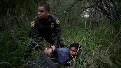 A border patrol agent apprehends a woman and a man after they were caught illegally crossing into the US border from Mexico near McAllen, Texas, on May 2, 2018. Reuters