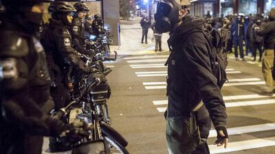 A protestor wearing a gas mask confronts police during a demonstration in Seatlle, following the decision by the grand jury not to charge the officer who shot Michael Brown. David Ryder/ Reuters