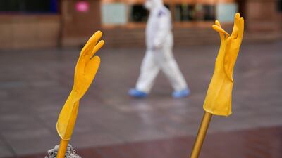 A pair of rubber gloves is hung to dry, as a security guard walks along a street in Shanghai. Reuters