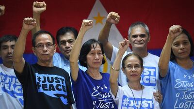 Communist rebel leader Benito Tiamzon, front left, his wife, Wilma, centre in blue, along with other rebel leaders raise their fists in Manila, hours after they were freed from detention at the police headquarters. Ted Aljibe / AFP Photo