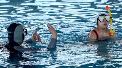 Iraqi female swimming coach Elaf, 35, teaches a child how to swim and dive, at a swimming pool in Basra. Reuters
