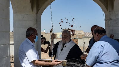 People gather as a priest rings the newly inaugurated bell at Syriac Christian church of Mar Tuma in Iraq's second city of Mosul, in the northern Nineveh province, on September 18, 2021. - The church bell was inaugurated today to the cheers of Iraqi Christians, seven years after the Islamic State group (IS) overran the city and proclaimed it their "capital", before they were driven out three years later by the Iraqi army after months of gruelling street fighting. (Photo by Zaid AL-OBEIDI / AFP)