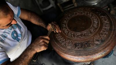 In this photo, Ahmad Zuhdi Ghazoul works on a piece of copper on the newly renovated copper market in Aleppo, Syria. He has been a copper worker for three decades.AP