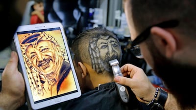 In this Friday, July 14, 2017 photo, Muhannad Khaled Omar, shaves an image of the late Palestinian leader Yasser Arafat on the back of a customer's head at his barber shop in Burj al-Barajneh, southern Beirut, Lebanon. In a city full of hair stylists, Omar stands out. He is a 26 year-old Palestinian-Syrian hair stylist known for shaving celebrity portraits into clients’ hair. (AP Photo/Bilal Hussein)