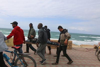 Displaced Palestinians carry an injured man after fleeing Al Shifa Hospital in Gaza city on Monday. Bloomberg