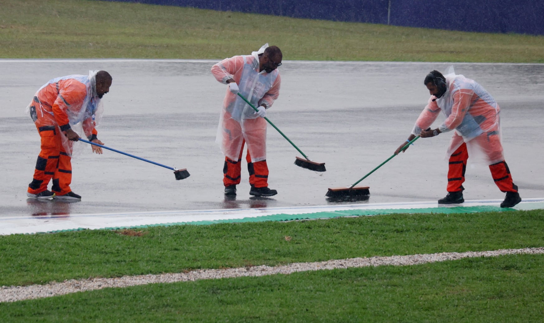 Marshals clear water from the track before the race. Reuters