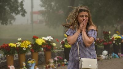 A mourner near flowers and teddies left to honour the victims of the Kremenchuk shopping mall attack. EPA