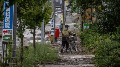 A man pushes his bicycle along a muddy pavement after heavy rain in Wajima city of Ishikawa prefecture. AFP