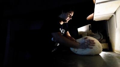 A pizza maker uses battery powered lamps to illuminate his work space during a blackout inside the delivery-only pizza shop in Buenos Aires, Argentina. AP