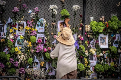 A woman adds flowers to a memorial featuring photos of some of those lost in the partially collapsed 12-storey Champlain Towers South building in Surfside, Florida. AFP