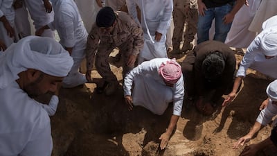 Friends and family pay their respects as Hayayei's body is lowered into a grave. Antonie Robertson / The National