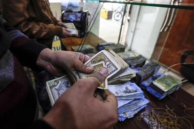 An employee of a currency exchange counter counts banknotes at a market street in the northeastern Syrian town of Qamishli. Delil souleiman / AFP