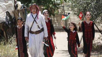 Palestinian refugee Mahmoud Abu Deeb, 82, a former fighter from the village of Beersheba, walks with family members outside his home in Khan Yunis in the southern Gaza Strip. AFP