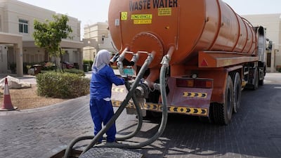 A worker disconnects hoses on a tanker after extracting sewage from a manhole in Al Ghadeer, Abu Dhabi. Delores Johnson / The National